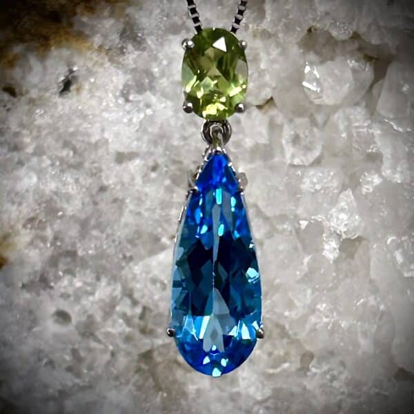 Blue Topaz And Peridot Pendant Set In A White Organic Background